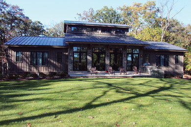 Modelo de fachada de casa marrón campestre grande de una planta con revestimiento de madera, tejado a dos aguas y tejado de metal