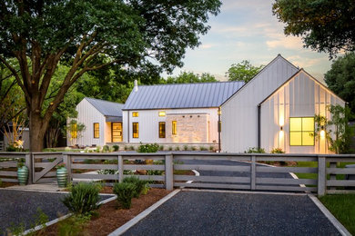 This is an example of a large and white farmhouse two floor house exterior in Dallas with wood cladding and a pitched roof.