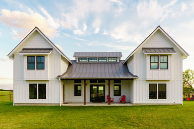 Ejemplo de fachada de casa blanca de estilo de casa de campo de tamaño medio de dos plantas con revestimiento de aglomerado de cemento, tejado a dos aguas y tejado de metal