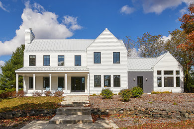Imagen de fachada de casa blanca campestre grande de dos plantas con revestimientos combinados, tejado a dos aguas y tejado de metal
