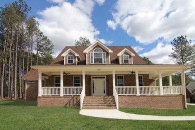 Foto della facciata di una casa grande beige country a due piani con rivestimento in mattoni e tetto a capanna