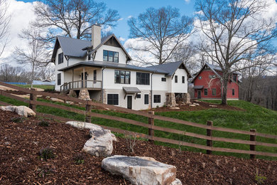 Example of a large cottage white two-story concrete fiberboard house exterior design in Other with a clipped gable roof and a metal roof