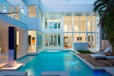 Large trendy white three-story stucco exterior home photo in Miami