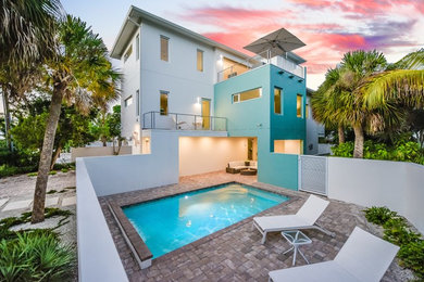 Inspiration for a mid-sized modern multicolored two-story stucco house exterior remodel in Tampa with a hip roof and a metal roof