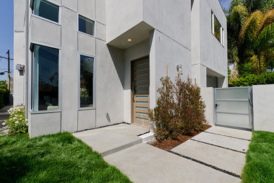Cette image montre une grande façade de maison grise minimaliste en béton à un étage avec un toit plat et un toit en métal.