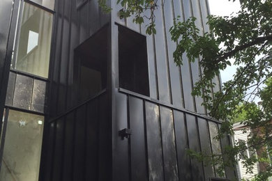 Photo of a black contemporary house exterior in Toronto with metal cladding.