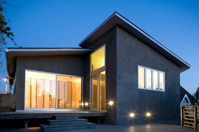На фото: двухэтажный, бежевый дом среднего размера в стиле модернизм с облицовкой из цементной штукатурки и плоской крышей с