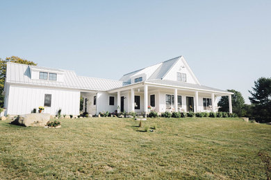 Ejemplo de fachada de casa blanca de estilo de casa de campo de tamaño medio de dos plantas con revestimiento de aglomerado de cemento y tejado de metal