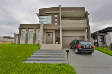 This is an example of a large and beige modern two floor brick detached house in Sydney with a flat roof and a metal roof.