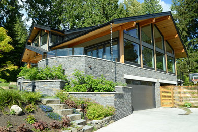Modelo de fachada de casa gris actual extra grande de dos plantas con revestimientos combinados, tejado a dos aguas y tejado de teja de madera