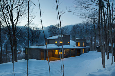 Diseño de fachada de casa gris actual grande de dos plantas con revestimientos combinados y tejado de teja de barro