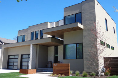 Aménagement d'une grande façade de maison beige moderne en stuc à un étage avec un toit plat.