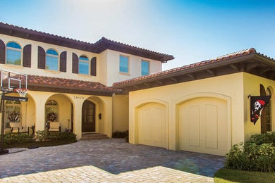 Mid-sized mediterranean beige two-story stucco exterior home idea in Tampa with a hip roof and a tile roof
