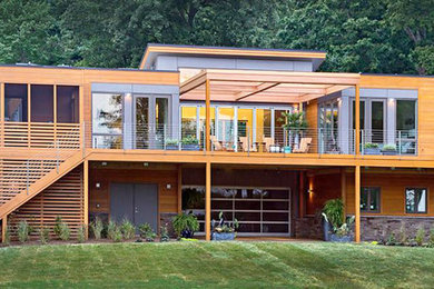 Пример оригинального дизайна: огромный, двухэтажный, деревянный, коричневый дом в современном стиле с плоской крышей