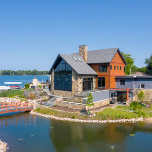 Réalisation d'une façade de maison orange chalet à un étage avec un revêtement en panneau de béton fibré, un toit à deux pans et un toit en shingle.