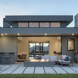 Large modern gray one-story stucco exterior home idea in Other with a metal roof