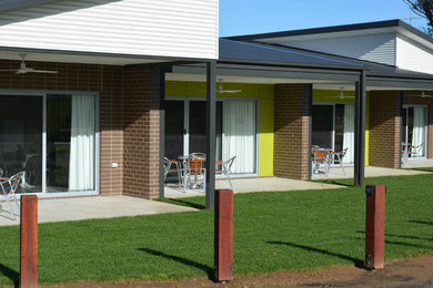 Immagine della facciata di un appartamento marrone contemporaneo a un piano con rivestimenti misti e copertura in metallo o lamiera