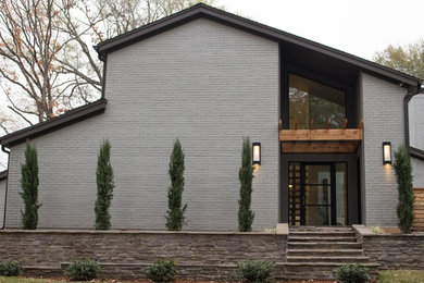 Immagine della facciata di una casa grande grigia moderna a due piani con rivestimenti misti e copertura a scandole