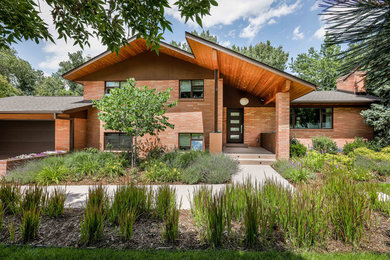 Diseño de fachada de casa roja minimalista grande de dos plantas con revestimiento de ladrillo y tejado de teja de madera