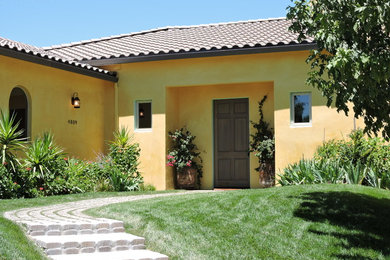 Large mediterranean yellow one-story stucco house exterior idea in Sacramento with a hip roof and a tile roof
