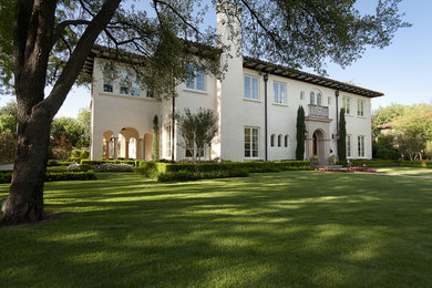 This is an example of a large and white mediterranean two floor render house exterior in Dallas with a hip roof.