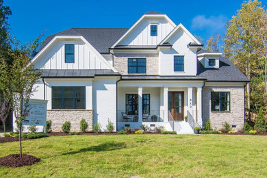 Example of a large trendy white three-story stone house exterior design in Raleigh