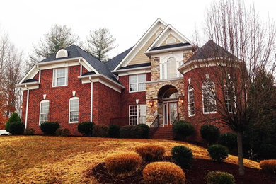 Large elegant red two-story brick exterior home photo in Charlotte with a hip roof