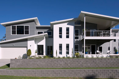 Imagen de fachada blanca clásica de dos plantas con revestimiento de aglomerado de cemento