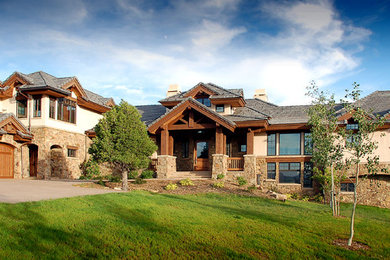 Cette photo montre une très grande façade de maison beige montagne à un étage avec un revêtement mixte et un toit à deux pans.