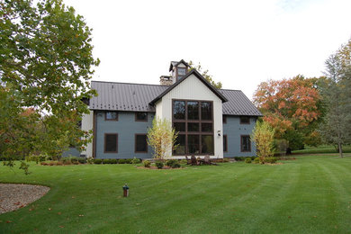 Immagine della villa grande blu eclettica a due piani con tetto a capanna, copertura in metallo o lamiera e rivestimento in legno