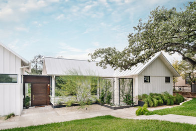 Ejemplo de fachada de casa blanca actual grande de una planta con tejado a dos aguas y tejado de metal