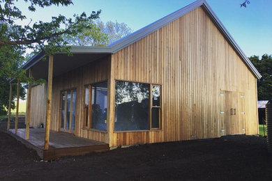 Ejemplo de fachada marrón de dos plantas con revestimiento de madera, tejado a dos aguas y tejado de metal