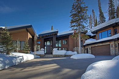 Exemple d'une très grande façade de maison marron tendance en bois à un étage avec un toit mixte, un toit noir et un toit en appentis.