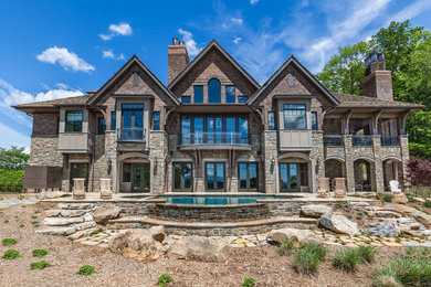Large rustic two-story stone house exterior idea in Other