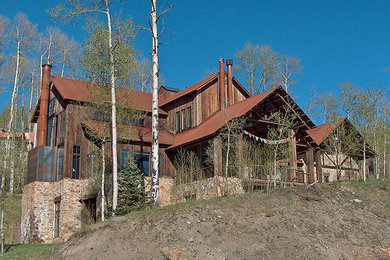 Foto de fachada de casa marrón rústica grande de tres plantas con revestimiento de madera, tejado a dos aguas y tejado de metal