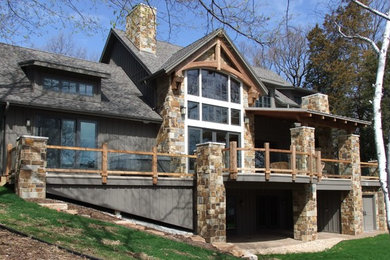 Mid-sized elegant gray two-story stone house exterior photo in Milwaukee with a hip roof and a tile roof