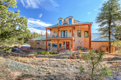 Large cottage beige two-story stucco exterior home photo in Albuquerque with a metal roof