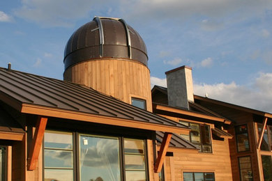 Ejemplo de fachada marrón minimalista extra grande de dos plantas con revestimiento de madera y tejado a dos aguas