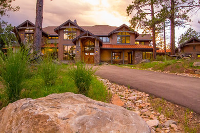 Inspiration pour une très grande façade de maison marron chalet à deux étages et plus avec un toit à deux pans et un toit mixte.