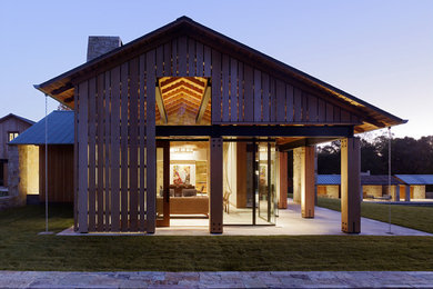 Esempio della facciata di una casa marrone country con rivestimento in legno e tetto a capanna