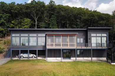 This is an example of a large and brown contemporary two floor detached house in New York with wood cladding, a flat roof and a metal roof.