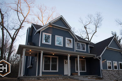 Diseño de fachada de casa azul marinera de dos plantas con revestimiento de vinilo y tejado de teja de madera