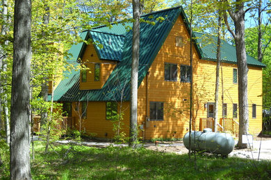 Example of a mid-sized mountain style brown wood exterior home design in Other with a metal roof