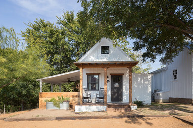 Example of a small country white one-story wood house exterior design in Austin with a metal roof