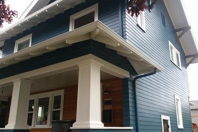 Diseño de fachada de casa azul tradicional de tamaño medio de dos plantas con revestimiento de vinilo, tejado a cuatro aguas y tejado de teja de madera