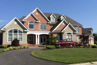 Large transitional gray two-story brick house exterior photo in Other with a hip roof and a shingle roof