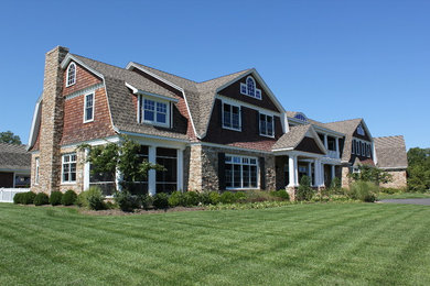 Example of a large country brown two-story wood house exterior design in Other with a gambrel roof and a shingle roof