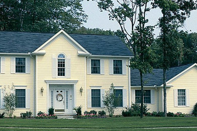 Example of a yellow two-story vinyl exterior home design in Boston