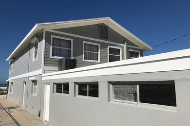 Modelo de fachada de casa gris marinera de tamaño medio de dos plantas con revestimiento de madera, tejado a dos aguas y tejado de teja de madera