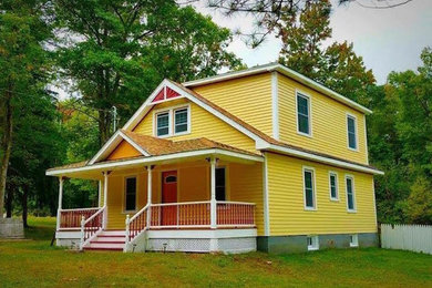 Diseño de fachada de casa amarilla tradicional de tamaño medio de dos plantas con revestimiento de vinilo, tejado a dos aguas y tejado de teja de madera